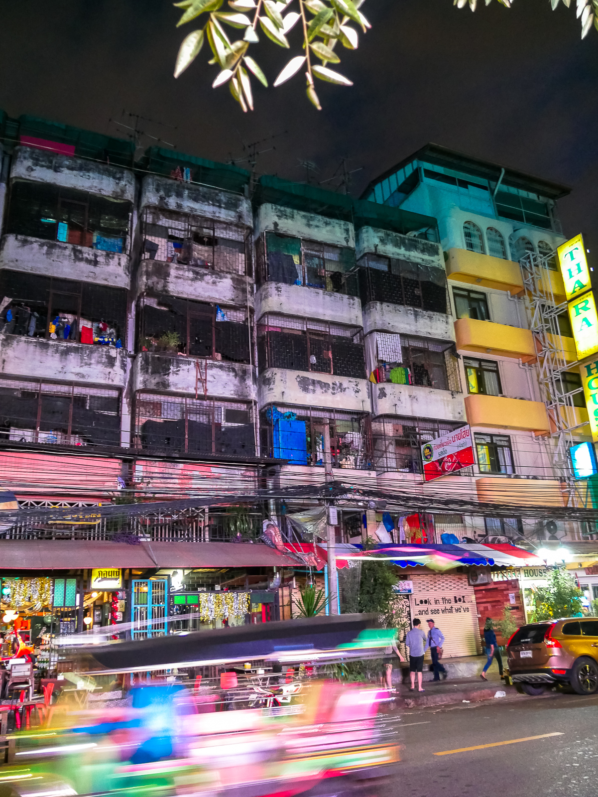 Tuk-tuk whizzes by a street at night in Bangkok